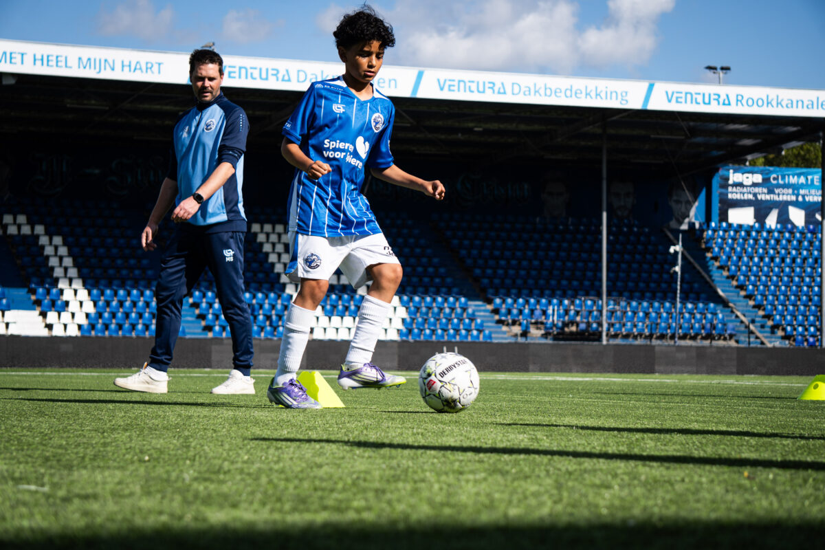 Voetbaltrainer geeft training aan jeugdspelers in Den Bosch